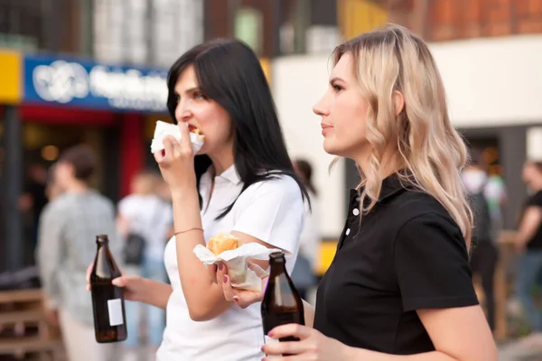 Mulheres muito jovens comendo hambúrguer ao ar livre na rua — Fotografia de Stock