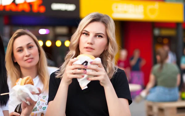 Mulheres muito jovens comendo hambúrguer ao ar livre na rua — Fotografia de Stock