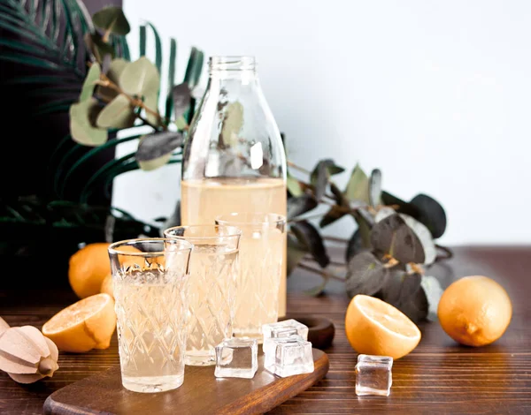 Bebida italiana licor de limón limoncello en una botella y vasos vacíos en la mesa de madera — Foto de Stock
