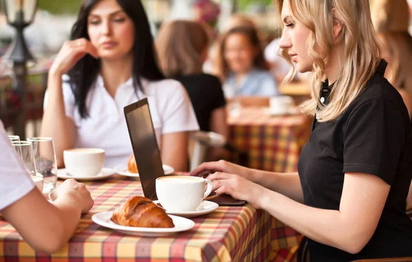 Mulheres bonitas trabalhadores ou estudantes usando laptop no café e conversando — Fotografia de Stock