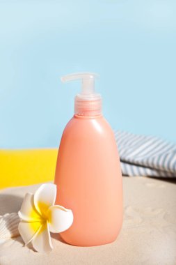 Yaz plajı, seyahat, tatil, tatil konsepti. Güneş kremi tübü, kumdaki plumeria frangipani