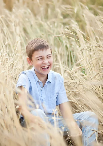 Niño adolescente en el campo de trigo en un día de verano — Foto de Stock