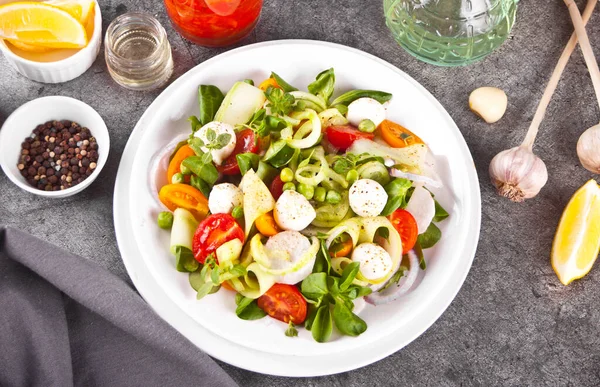 Sallad av färska körsbärstomater, mozzarella, basilika och andra grönsaker på middagsbordet — Stockfoto