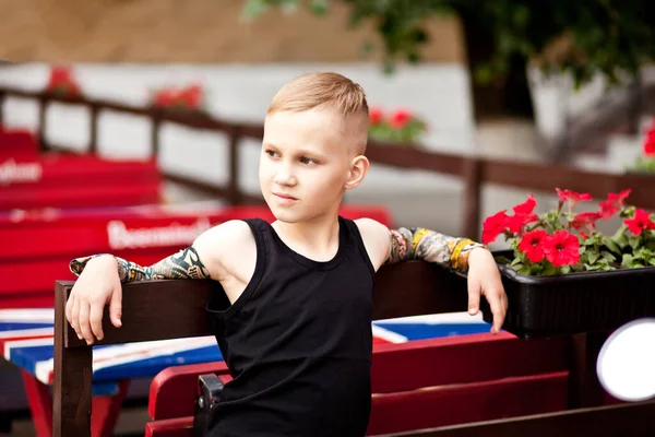 Mode liten blond pojke unge bär med tatuering ärmar och svart t-shirt — Stockfoto