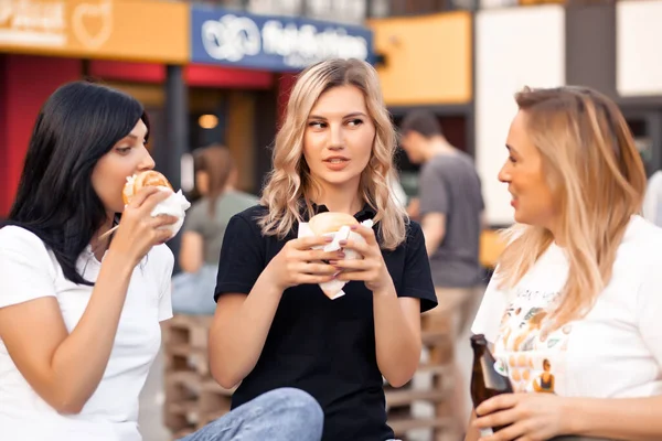 Mulheres muito jovens comendo hambúrguer ao ar livre na rua — Fotografia de Stock