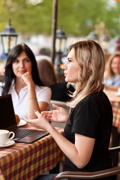 Mulheres bonitas trabalhadores ou estudantes usando laptop no café e conversando — Fotografia de Stock