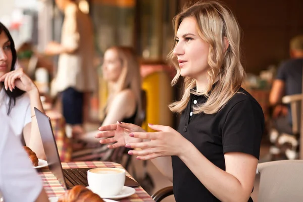 Mulheres bonitas trabalhadores ou estudantes usando laptop no café e conversando — Fotografia de Stock