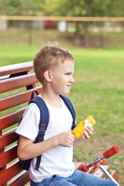 Parktaki bankta oturan ve taze haşlanmış mısır yiyen bir çocuk..