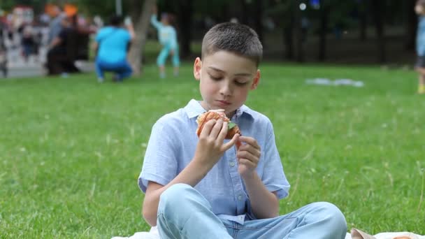 Jongen kind zit op picknick zomervakantie en het eten van vers gebakken croissant sandwich — Stockvideo