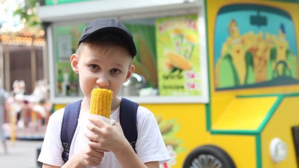 男孩在街市吃新鲜煮熟的玉米 — 图库视频影像
