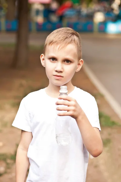 Kleiner Junge trinkt Wasser aus Flasche im Freien in einem Park — Stockfoto