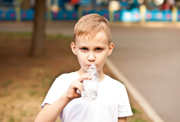 Kleiner Junge trinkt Wasser aus Flasche im Freien in einem Park — Stockfoto