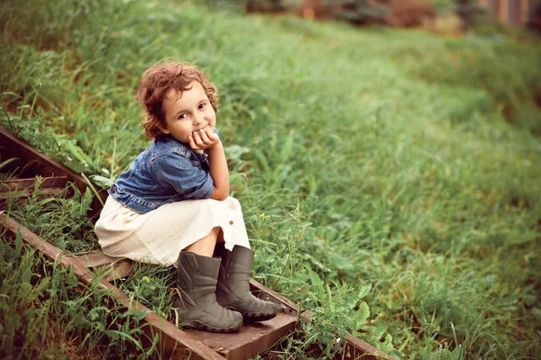Küçük mutlu kız tahta merdivenlerde oturuyor. Yaz kır hayatı. — Stok fotoğraf