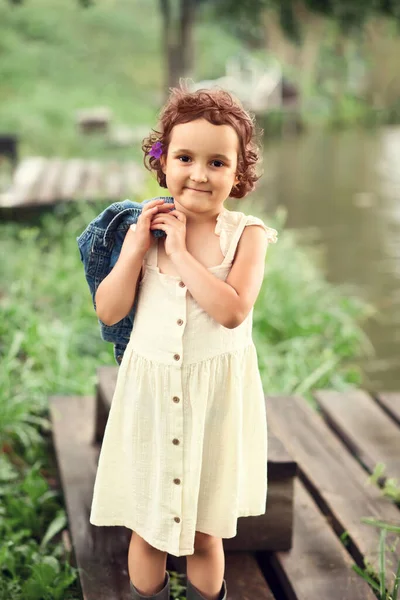 Маленька щаслива дівчинка в селі біля річки або озера. Літнє сільське життя . — стокове фото