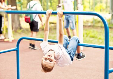 Parktaki parkta spor antrenman aleti olan genç bir çocuk..