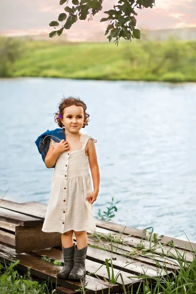 Pequena menina feliz na aldeia perto de rio ou lago. Verão país vida. — Fotografia de Stock