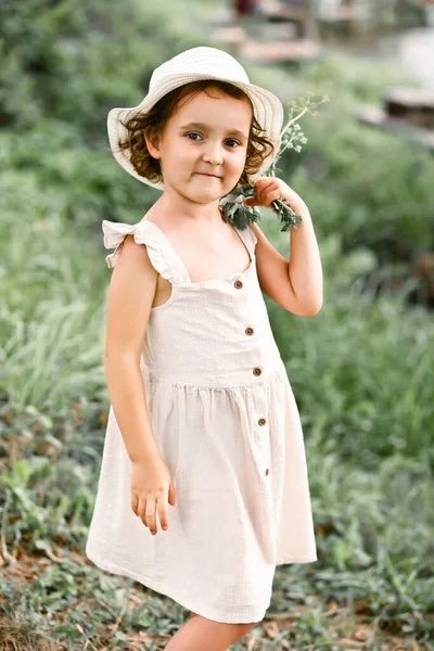 Mała szczęśliwa dziewczynka w wiosce w pobliżu rzeki lub jeziora. Letnie życie na wsi. — Zdjęcie stockowe