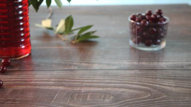 Woman hand put on a table tray with glasses of cherry brandy liqueur with ripe berries