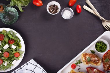 Tepside et, pirinç ve sebze ile doldurulmuş biber ve siyah arka planda yeşil, domates ve peynir ile salata. Üst Manzara. Boşluğu kopyala.