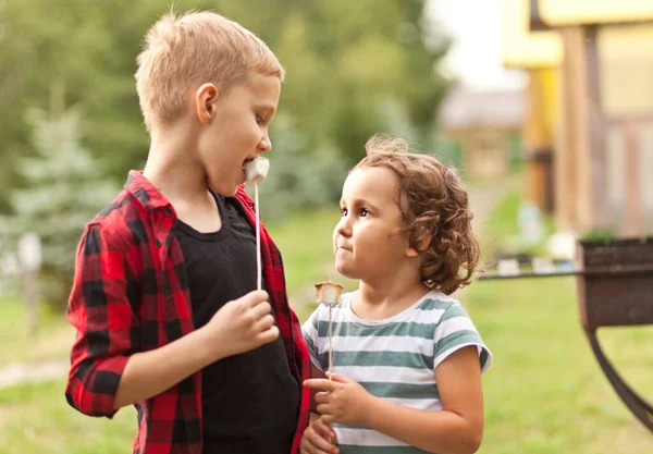 Teen chlapec a dívka dítě jíst pečené marshmalloy venkovní v táboře. Cestování, túra, dovolená, koncept kempování. — Stock fotografie