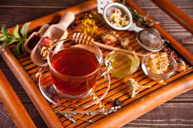 Bir fincan çiçekli bitki çayı ve çeşitli kurutulmuş otlar..