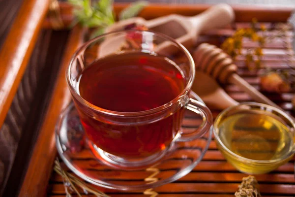 Taza de té de hierbas con un tazón pequeño con miel en la bandeja. — Foto de Stock