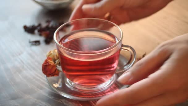 Woman hand put a cup of hibiscus rose tea on table — kuvapankkivideo