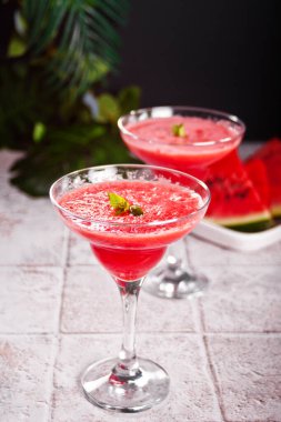 Karpuz ferahlatıcı yaz kokteyli. Arka planda karpuz dilimleri ve parçaları var.