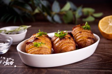 Geleneksel Amerikan ev yapımı Hasselback Patates ve taze otlarla doldurulmuş patates ve domuz pastırması..