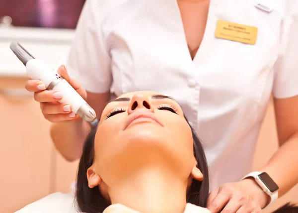 Woman lying on a table with protect glasses on eyes have a laser skin treatment. Beauty spa salon.