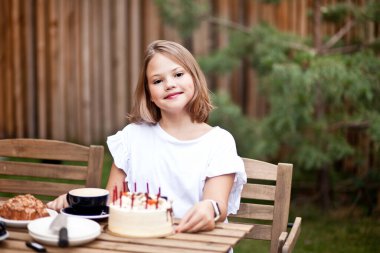 Kafe terasında doğum günü pastası yiyen mutlu tatlı kız. 10 yaşındaki bir çocuk doğum gününü kutlar..