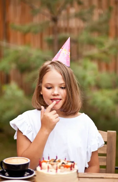 Szczęśliwa urocza dziewczyna je tort urodzinowy w kawiarni taras. 10 lat świętować urodziny. — Zdjęcie stockowe