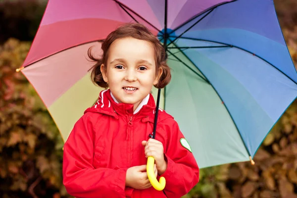 Criança com guarda-chuva arco-íris multicolorido ao ar livre — Fotografia de Stock