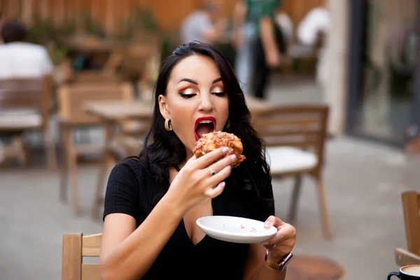 Vacker kvinna dricker kaffe på ett café och äter croissant — Stockfoto