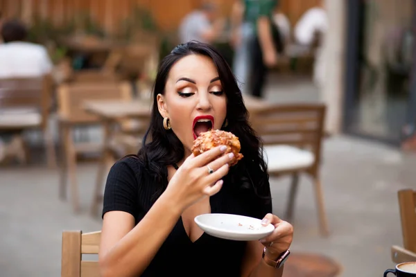 Mulher bonita bebendo café em um café e comer croissant — Fotografia de Stock