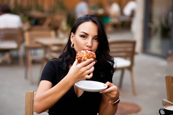 Mulher bonita bebendo café em um café e comer croissant — Fotografia de Stock