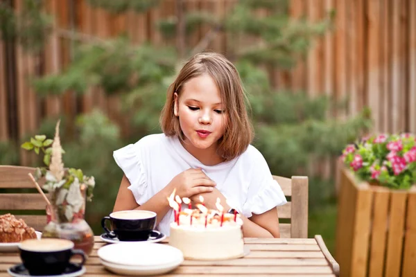 Счастливая обожаемая девушка ест именинный торт на террасе кафе. 10-летние отмечают день рождения. — стоковое фото