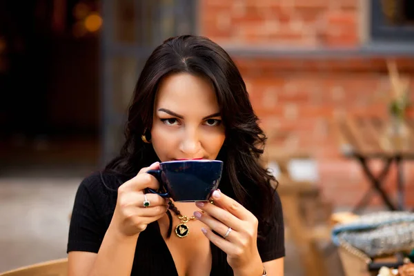 Mulher bonita bebendo café em um café e comer croissant — Fotografia de Stock