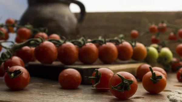 Cherry tomatoes on display on wooden chopping board and wooden table. — Stock Photo, Image