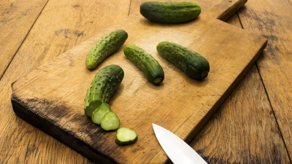 Cucumbers on wooden chopping board and table.