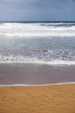 Sahildeki dalgalar kumsaldaki kuma ulaşıyor.