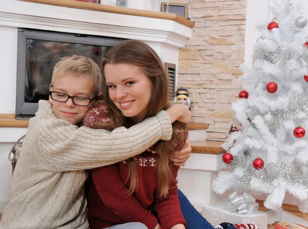 खुश भाई एक क्रिसमस पेड़ के पास अपनी बहन को गले लगा रहा है — स्टॉक फ़ोटो, इमेज