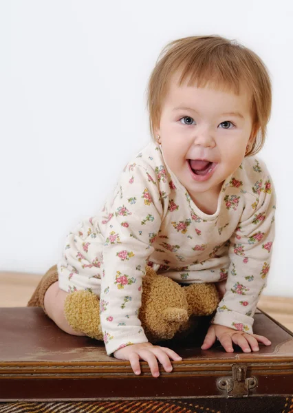 Joyfool little girl sitting on a suitcase and smile — Stock Photo, Image