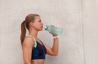 Sabahın köründe koştuktan sonra mola verip su içen sportif bir kadın. Sağlıklı yaşam tarzı kavramı.