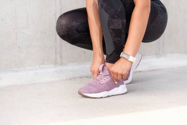 Spor ayakkabıların bağcıklarını bağlayan kadınların el çekimlerini yakından çek. Sporcu kadın koşuya hazırlanıyor. Sağlıklı yaşam tarzı kavramı.