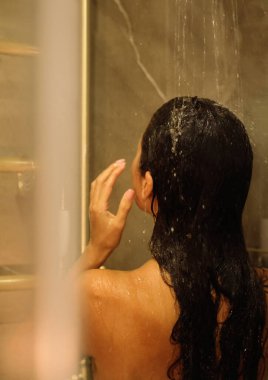 Güzel, çıplak genç bir kadının banyoda duş alışının arkası. Güzellik merkezi konsepti.