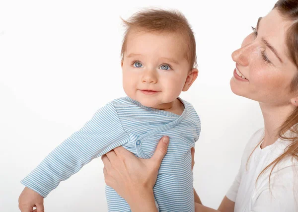 妈妈抱着可爱的快乐的小男孩 蓝眼睛 背景是白色的 快乐童年和母性概念 图库图片