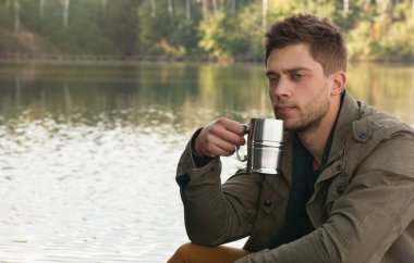 handsome attractive man at the lake on beautiful nature backgrou clipart