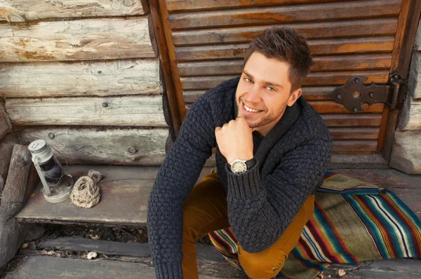 Young handsome fashionable man by the wooden coutry house backgr — Stock Photo, Image