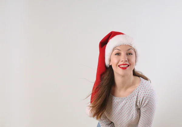 Attraente sorridente giovane donna in cappello di Babbo Natale su sfondo bianco — Foto Stock